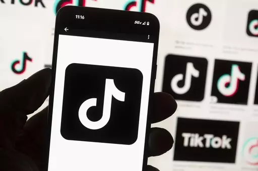 The TikTok logo is seen on a mobile phone in front of a computer screen which displays the TikTok home screen, Oct. 14, 2022, in Boston. Lawmakers in Georgia, early Friday, March 29, 2024, approved a bill that would require parental permission before children younger than 16 could sign up for social media accounts. (AP Photo/Michael Dwyer, File)