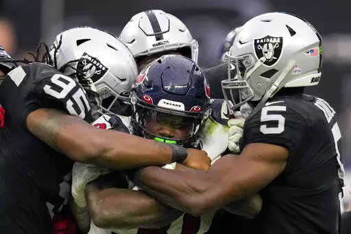 Houston Texans running back Dameon Pierce, center, is brought down by Las Vegas Raiders defensive tackle Kendal Vickers (95), linebacker Divine Deablo (5) and others during the second half of an NFL football game Sunday, Oct. 23, 2022, in Las Vegas. (AP Photo/John Locher)