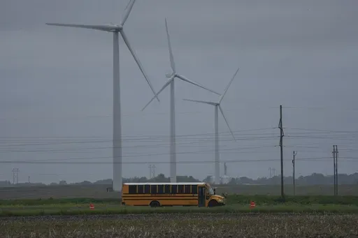 A school bus drives down a road near a field of wind turbines, Thursday, May 9, 2024, in Paxton, Ill. (AP Photo/Joshua A. Bickel)