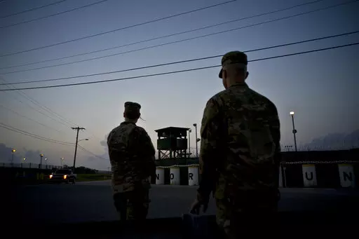 In this June 5, 2018 photo, reviewed by U.S. military officials, troops stand guard outside Camp Delta at the Guantanamo Bay detention center, in Cuba. The 20th anniversary of the first prisoners' arrival at the Guantanamo Bay detention center is on Tuesday, Jan. 11, 2022. There are now 39 prisoners left. At its peak, in 2003, the detention center held nearly 680 prisoners. (AP Photo/Ramon Espinosa, File)