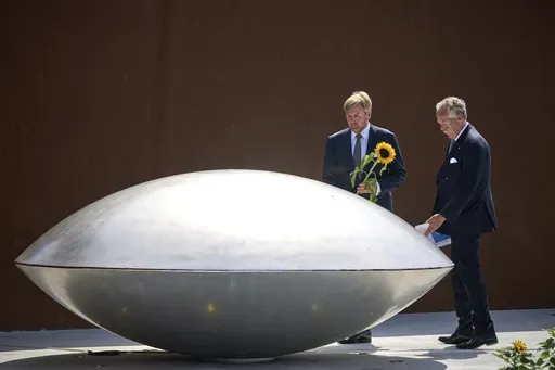 Dutch King Willem Alexander, left, together with Piet Ploeg, lay flowers during the commemoration at the national monument in Vijfhuizen, Netherlands, Wednesday July 17, 2024, to mark the tenth anniversary of the downing of flight MH17 in eastern Ukraine, which killed all 298 people on board. (AP Photo/Phil Nijhuis)