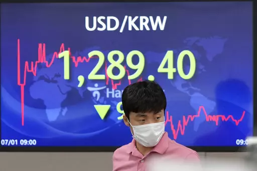 A currency trader walks by the screen showing the foreign exchange rate between U.S. dollar and South Korean won at a foreign exchange dealing room in Seoul, South Korea, Friday, July 1, 2022. Asian benchmarks were mostly lower on Friday, echoing a decline on Wall Street, after a quarterly report by Japan’s central bank rekindled worries about the world’s third largest economy. (AP Photo/Lee Jin-man)