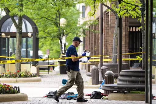 Members of the FBI's Evidence Response Team Unit investigate on Central Avenue near Green Bay Road in downtown Highland Park, Ill., less than 24 hours after a gunman killed several people and wounded dozens more by firing a high-powered rifle from a rooftop onto a crowd attending Highland Park's Fourth of July parade, Tuesday morning, July 5, 2022. (Ashlee Rezin/Chicago Sun-Times via AP)