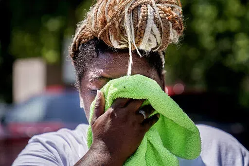 Nicole Brown wipes sweat from her face while setting up her beverage stand near the National Mall on July 22, 2022, in Washington. What's considered officially “dangerous heat” in coming decades will likely hit much of the world at least three times more often as climate change worsens, according to a new study. (AP Photo/Nathan Howard, File)
