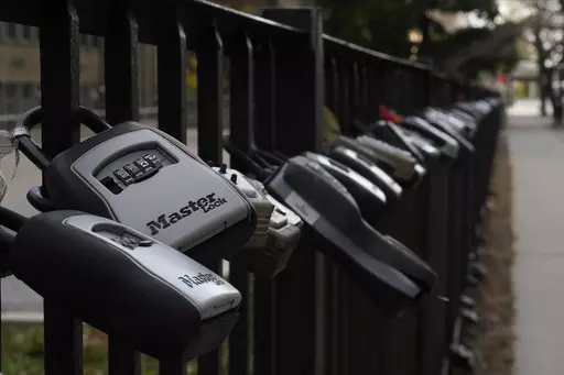 Key lock boxes for real estate showings hang on a fence outside a high-rise condominium building, Oct. 27, 2022, in Chicago. The cost of hiring a real estate agent to buy or sell a home is poised to change along with decades-old rules that have helped determine broker commissions. (AP Photo/Kiichiro Sato, File)