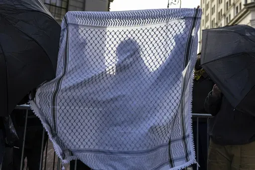 A student from Columbia University holds up a keffiyeh as they line up to enter Manhattan federal court to attend the deportation case of Mahmoud Khalil, Wednesday, March 12, 2025, in New York. (AP Photo/Stefan Jeremiah)