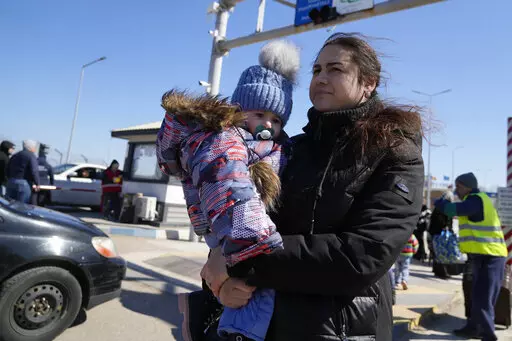 A woman carries her baby after fleeing the war from neighbouring Ukraine at the border crossing in Palanca, Moldova, Saturday, March 19, 2022. (AP Photo/Sergei Grits)