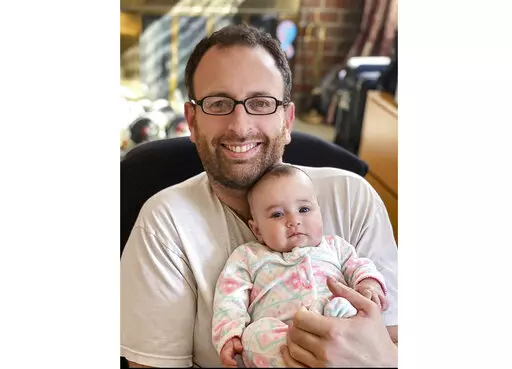 In this Oct. 2020 photo released by Eugene Brusilovskiy, Eugene holds his then-3-month-old daughter, Aya, in Philadelphia. Since Aya was born in the early months of the pandemic, Brusilovskiy was able to stay at home and spend time with her. A survey from the U.S. Census Bureau says parents shared more time with their children from March to June 2020, when coronavirus-lockdowns were at their most intense in many part of the U.S., than they had in previous years. (Eugene Brusilovskiy via AP)