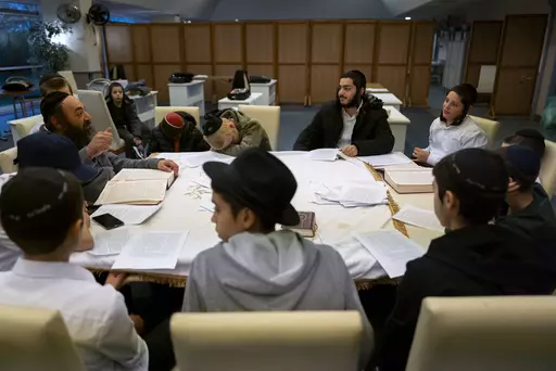 Young refugees from Israel listen to a rabbi in a Yashiva in a Jewish refugee camp in Balatonoszod, Hungary, Tuesday Nov. 7, 2023. The camp, which houses around 250 people, including 100 children, provides shelter for Jewish refugees, some of whom escaped war both in Ukraine and Israel. (AP Photo/Bela Szandelszky)