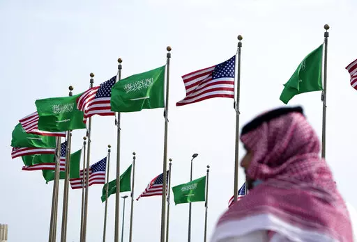 A man stands under American and Saudi Arabian flags prior to a visit by U. S. President Joe Biden, at a square in Jeddah, Saudi Arabia, Thursday, July 14, 2022. As President Joe Biden prepares to meet Saudi Crown Prince Mohammed bin Salman on Friday, the prince's reputation as a brazen leader whose rise to power coincided with a sweeping crackdown on critics will likely cast a shadow on the meeting. (AP Photo/Amr Nabil, File)