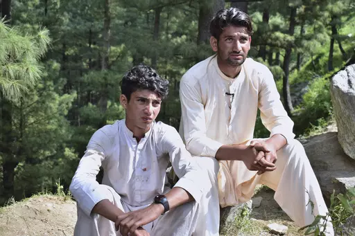 Abrar Ahmed, left, a survivor of cable car incident, sits with his cousin as he talks to members of media, near the incident site, in Pashto village, a mountainous area of Battagram district in Pakistan's Khyber Pakhtunkhwa province, Wednesday, Aug. 23, 2023. The rescue of six school children and two adults who were plucked from a broken cable car that was dangling precariously hundreds of meters (yards) above a steep gorge was a miracle, a survivor said Wednesday. The teenager said he and the o