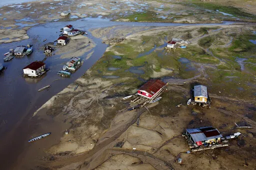 Houseboats sit amid drought-impacted land near the Solimões River, in Tefe, Amazonas state, Brazil, Wednesday, Oct. 19, 2022. Months after enduring floods that destroyed crops, thousands of families in the Brazilian Amazon are now dealing with severe drought. (AP Photo/Edmar Barros)