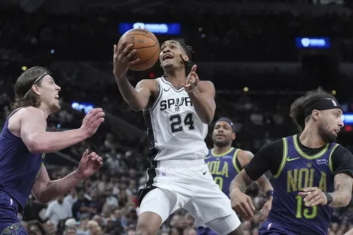 San Antonio Spurs guard Devin Vassell (24) drives to the basket against New Orleans Pelicans forward Kelly Olynyk, left, during the first half of an NBA basketball game in San Antonio, Saturday, March 15, 2025. (AP Photo/Eric Gay)