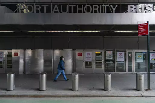 A pedestrian passes the 9th Avenue shuttered doors of the Port Authority Bus Terminal, Friday, Jan. 22, 2021, in New York. The police agency that patrols New York City’s main bus terminal has agreed to stop sending plainclothes officers into its public bathrooms to try and catch people propositioning strangers for sex, a type of sting long criticized by activists as a discriminatory relic of an era of crackdowns predominantly aimed at gay men. (AP Photo/Mary Altaffer, File)
