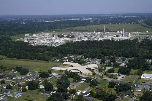 The Fifth Ward Elementary School and residential neighborhoods sit near the Denka Performance Elastomer Plant, back, in Reserve, La., Friday, Sept. 23, 2022. Denka Performance Elastomer in Louisiana threatened to shut down if the Biden administration doesn’t give it more time to reduce its emissions. The company makes the synthetic rubber neoprene — and federal officials have accused the plant of increasing cancer risk to the nearby, majority-Black community. (AP Photo/Gerald Herbert, File)
