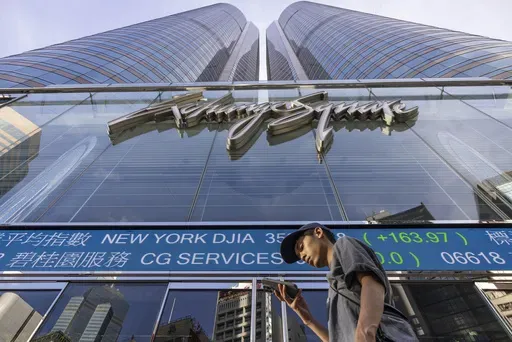 A pedestrian passes by a Hong Kong Stock Exchange electronic screen in Hong Kong on July 21, 2023. China stocks were mixed Wednesday, March 13, 2024, as the country scrambled to avoid major real estate developer bankruptcy. (AP Photo/Louise Delmotte, File)