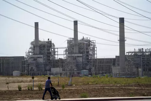 A man pushes a stroller near the AES power plant in Redondo Beach, Calif., Wednesday, Sept. 7, 2022. A record heat wave put California in a fossil fuel conundrum: The state has had to rely more heavily on natural gas to produce electricity and avoid power outages while Gov. Gavin Newsom's administration moves toward ending the use of oil and gas. (AP Photo/Jae C. Hong)