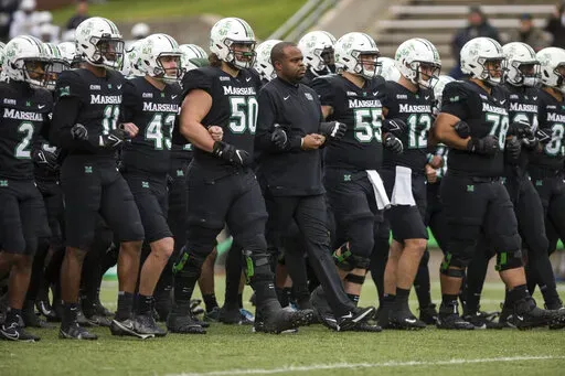 Marshall players and coaches take the field against UAB in an NCAA college football game on Saturday, Nov. 13, 2021, at Joan C. Edwards Stadium in Huntington W.Va. On Tuesday, March 29, 2022, Conference USA announced in a joint statement with Marshall, Old Dominion and Southern Miss that it has reached a resolution with the three schools to expedite their early move to the Sun Belt. (Sholten Singer/The Herald-Dispatch via AP, File)