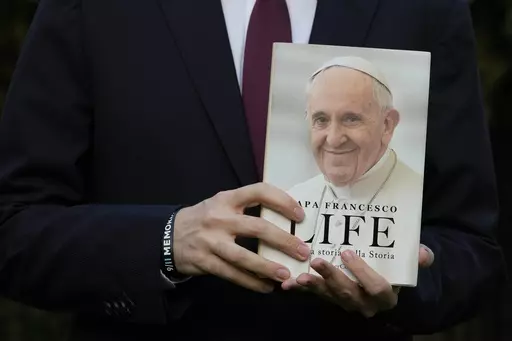 Italian journalist and writer Fabio Marchese Ragona holds a copy of "Life: My Story Through History" as he poses for a picture prior to the start of an interview with the Associated Press, in Rome, Thursday, March 13, 2024. Pope Francis says he has no plans to resign and isn't suffering from any health problems that would require doing so, in an autobiography, "Life: My Story Through History," which is being published Tuesday and written with Italian journalist Fabio Marchese Ragona. (AP Photo/G