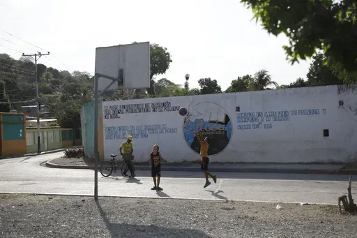A child shoots a basketball on a street court in Tocorón, Venezuela, Saturday, March 22, 2025. (AP Photo/Cristian Hernandez)