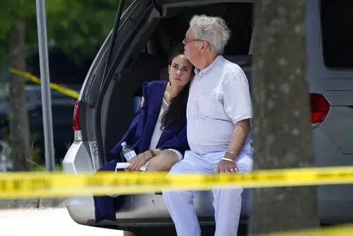 A man comforts a young woman wearing a graduation gown within the crime scene of a shooting at Xavier University in New Orleans, Tuesday, May 31, 2022. (AP Photo/Gerald Herbert)