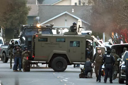 Law enforcement officers aim their weapons at a home during a standoff in Grants Pass, Ore., on Tuesday, Jan. 31, 2023. Police said the standoff involving a man suspected in a violent kidnapping in Oregon who was barricaded underneath the home has been “resolved.” (Scott Stoddard/Grants Pass Daily Courier via AP)