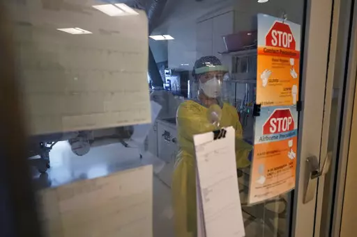 Registered nurse Morgan Flynn works inside a patient's room in the COVID-19 Intensive Care Unit at Dartmouth-Hitchcock Medical Center, in Lebanon, N.H., Monday, Jan. 3, 2022. Hospitalizations in U.S. children under age 5 with COVID have soared dramatically to unprecedented levels, a worrisone trend in youngsters too young to be vaccinated. (AP Photo/Steven Senne)
