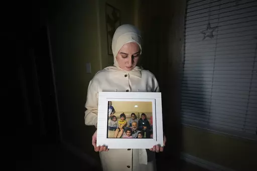 Maryam Kamalmaz hold a photo of her father with some of his 14 grandchildren in Grand Prairie, Texas, Jan. 17, 2024. By any standard, the past 18 months have been remarkable for getting wrongfully detained Americans home. But not so for Kamalmaz, who has had no trace of her father, Majd Kamalmaz, since the psychologist from Texas was stopped at a checkpoint in Syria in 2017 after traveling there to visit an elderly family member. He remains one of several Americans missing in Syria, including jo