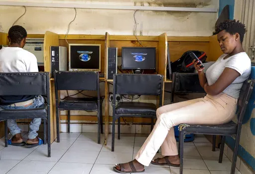 A customer uses the Wi-Fi on her mobile phone at an internet cafe in the low-income Kibera neighborhood of Nairobi, Kenya on Sept. 29, 2021. Facebook has failed to catch Islamic State group and al-Shabab extremist content in posts aimed at East Africa as the region remains under threat from violent attacks and Kenya prepares to vote in a closely contested national election, according to a new study released Wednesday, June 15, 2022. (AP Photo/Brian Inganga, File)
