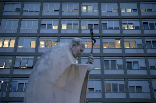 A marble statue of late Pope John Paul II is backdropped by the Agostino Gemelli Polyclinic in Rome, Saturday, Feb. 15, 2025, where Pope Francis was hospitalized Friday after a weeklong bout of bronchitis worsened and is receiving drug therapy for a respiratory tract infection. (AP Photo/Gregorio Borgia)