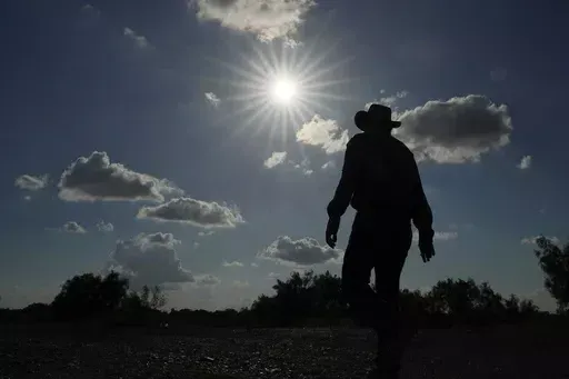 Jessie Fuentes, who works providing people with canoes and kayaks, walks along the Rio Grande with the sun pushing the temperature into the 90s on July 6, 2023. The death certificates of more than 2,300 people who died in the United States last summer mention the effects of excessive heat, the highest number in 45 years of records, according to an Associated Press analysis of Centers for Disease Control and Prevention data. With May already breaking heat records, 2024 could be even deadlier. (AP