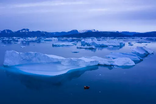 A boat navigates at night next to large icebergs near the town of Kulusuk, in eastern Greenland on Aug. 15, 2019. A sharp spike in Greenland temperatures since 1995 showed the giant northern island 2.7 degrees (1.5 degrees Celsius) hotter than its 20th-century average, the warmest in more than 1,000 years, according to new ice core data. (AP Photo/Felipe Dana, File)