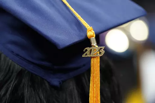 A tassel with 2023 on it rests on a graduation cap as students walk in a procession for Howard University's commencement in Washington, Saturday, May 13, 2023. A Biden administration rule aimed at making it easier to obtain student loan debt relief for people who say they were victims of misleading information about the quality of education they would receive at the colleges or universities where they enrolled was put on hold Monday, Aug. 7, by a federal appeals court in New Orleans. (AP Photo/A