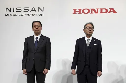 Nissan Chief Executive Makoto Uchida, left, Honda Chief Executive Toshihiro Mibe, right, with Takao Kato, CEO of Mitsubishi Motors, not in photo, pose for photographers during a joint news conference in Tokyo, Japan, on Dec. 23, 2024. (AP Photo/Eugene Hoshiko, File)