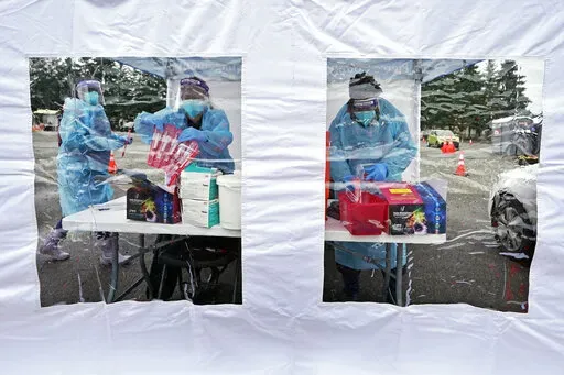 Workers at a drive-up COVID-19 testing clinic stand in a tent as they prepare PCR coronavirus tests, Jan. 4, 2022, in Puyallup, Wash., south of Seattle. Testing for COVID-19 has plummeted across the globe, dropping by 70 to 90% worldwide from the first to the second quarter of 2022, making it much tougher for scientists to track the course of the pandemic and spot new, worrisome viral mutants as they emerge and spread. (AP Photo/Ted S. Warren, File)