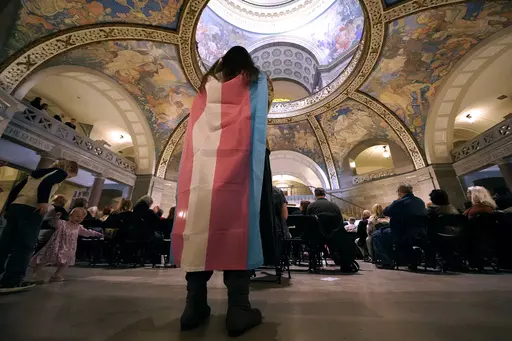 Glenda Starke wears a transgender flag as a counter protest during a rally in favor of a ban on gender-affirming health care legislation, March 20, 2023, at the Missouri Statehouse in Jefferson City, Mo. A judge's ruling striking down Arkansas' first-in-the-nation ban on gender-affirming care for minors, on June 20, is offering hope to transgender people, families and providers after a historic wave of restrictions on trans people's lives sailed through Republican statehouses this year. (AP Phot