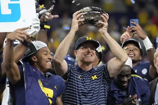Michigan head coach Jim Harbaugh holds the trophy as he celebrates with his team after defeating Purdue in the Big Ten championship NCAA college football game, early Sunday, Dec. 4, 2022, in Indianapolis. There could be some awkward trophy ceremonies around college football's championship weekend. (AP Photo/AJ Mast, File)