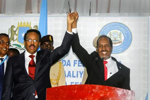 Hassan Sheikh Mohamud, right, marks his election win with incumbent leader Mohamed Abdullahi Mohamed, left, at the Halane military camp in Mogadishu, Somalia, Sunday, May 15, 2022. Former President Mohamud, who was voted out of power in 2017, has been returned to the nation's top office after defeating the incumbent leader in a protracted contest decided by legislators in a third round of voting late Sunday. (AP Photo/Farah Abdi Warsameh)