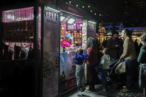 People wait in line for hot donuts at Bryant Park's Winter Village, Tuesday, Nov. 26, 2024, New York. (AP Photo/Julia Demaree Nikhinson, File)