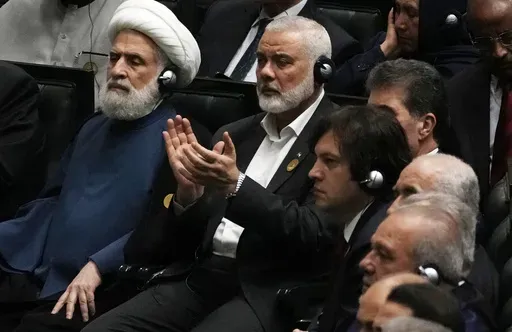 Hamas chief Ismail Haniyeh claps as newly-elected Iranian President Masoud Pezeshkian speaks while deputy leader of the Lebanese militant group Hezbollah, Sheikh Naim Kassem, left, sits during the swearing-in ceremony of Pezeshkian at the Iranian parliament, in Tehran, Iran, Tuesday, July 30, 2024. (AP Photo/Vahid Salemi)