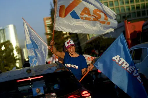 A follower of Chile's presidential candidate Jose Antonio Kast from the Partido Republicano, holds campaign flags during a rally in Santiago, Chile, Wednesday, Dec. 15, 2021. Chile votes in the runoff election on Dec. 19. (AP PhotoMatias Delacroix)