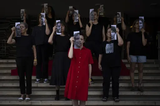 Relatives and supporters of Israeli hostages held by Hamas in Gaza hold photos of their loved ones during a performance calling for their return in Tel Aviv, Israel, Thursday, May 23, 2024. (AP Photo/Oded Balilty)