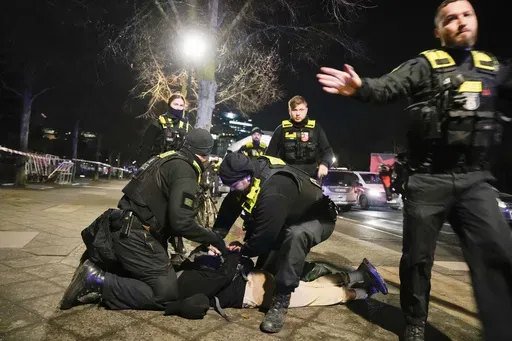 Police officers detain a man at the Holocaust memorial in Berlin, Germany, after another man was seriously injured, Friday, Feb. 21, 2025. (AP Photo/Ebrahim Noroozi)