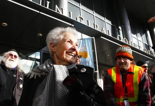 Dorli Rainey, 84, center, who was pepper-sprayed by police while taking part in an "Occupy Seattle" protest, smiles before speaking on Nov. 18, 2011, in front of police headquarters in downtown Seattle. Rainey, who became a symbol of the Occupy protest movement after she was pepper-sprayed by Seattle police in 2011, has died on Aug. 12, 2022, at age 95. Her daughter, Gabriele Rainey, said her mom was “so active because she loved this country, and she wanted to make sure that the country was go