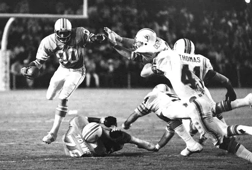 Miami Dolphin defenders Vern Den Herder and Norris Thomas (41) go after Houston Oilers wide receiver Ken Burrough (00) during the first half of an NFL football game Dec. 24, 1978, in Miami. Burrough, who was the last NFL player to wear No. 00, died Thursday, Feb. 24, 2022. He was 73. Burrough's family announced the death, saying died at his home in Jacksonville, Fla. (AP Photo, File)
