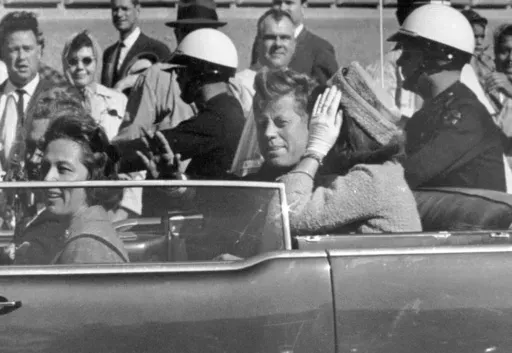 President John F. Kennedy waves from his car in a motorcade approximately one minute before he was shot, Nov. 22, 1963, in Dallas. Riding with President Kennedy are first lady Jacqueline Kennedy, right, Nellie Connally, second from left, and her husband, Texas Gov. John Connally, far left. (AP Photo/Jim Altgens, File)