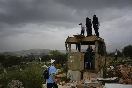 Israeli settlers stand in the outpost of Eviatar in the West Bank, Monday, April 10, 2023. Thousands led by hardline ultranationalist Jewish settlers marched to the unauthorized settlement outpost Eviatar in the northern West Bank that was cleared by the Israeli government in 2021, protected by a large contingent of Israeli soldiers and police. (AP Photo/Ariel Schalit)