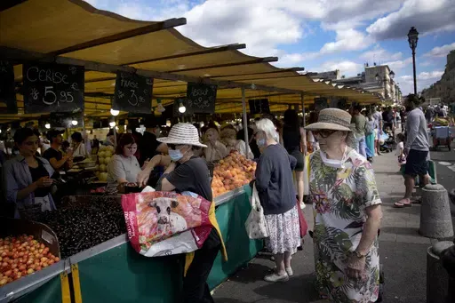 People shop at a market in Versailles, outside Paris, France, on July 3, 2022. From taxing billionaires and making gasoline cheaper to earlier retirement and higher wages, opposing left-right blocs in France's election are making costly campaign promises that are spooking investors as they seek to woo voters and sideline President Emmanuel Macron. (AP Photo/ Christophe Ena, File)