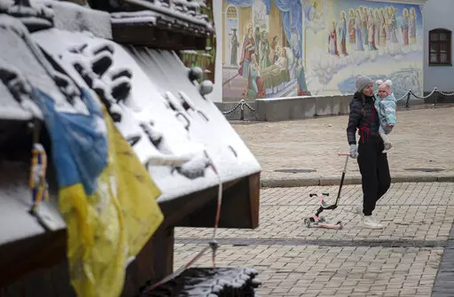 A woman walks past a display of destroyed Russian tanks and armoured vehicles after a snowfall in downtown Kyiv, Ukraine, Thursday, Nov. 17, 2022. (AP Photo/Andrew Kravchenko)