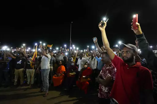 Sri Lankans hold up their mobile phone torches during a vigil condemning police shooting at protesters in Rambukkana, 90 kilometers (55 miles) northeast of Colombo, at a protest outside the president's office in Colombo, Sri Lanka, Tuesday, April 19, 2022. Sri Lankan police opened fire Tuesday at a group of people protesting new fuel price increases, killing one and injuring 10 others, in the first shooting by security forces during weeks of demonstrations over the country's worst economic crisi